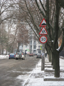 Close up of the street sign - top warns of speed bumps on road, then children crossing, then 30 km/hour