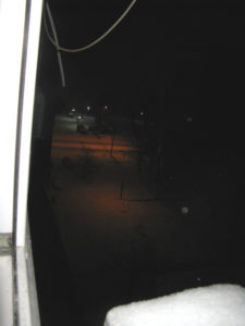 It is kind of dark but maybe you can see the road that has new snow and no one has driven on it yet.  It is early morning so it is pretty dark outside.