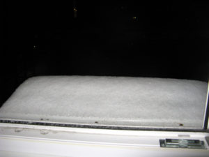 The snow is built up on our air conditioner our our balcon window.