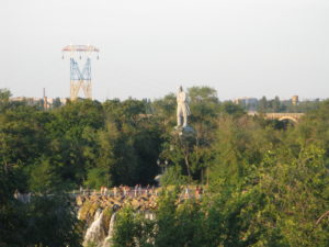 The statue on the island really stands tall over the waterfalls.